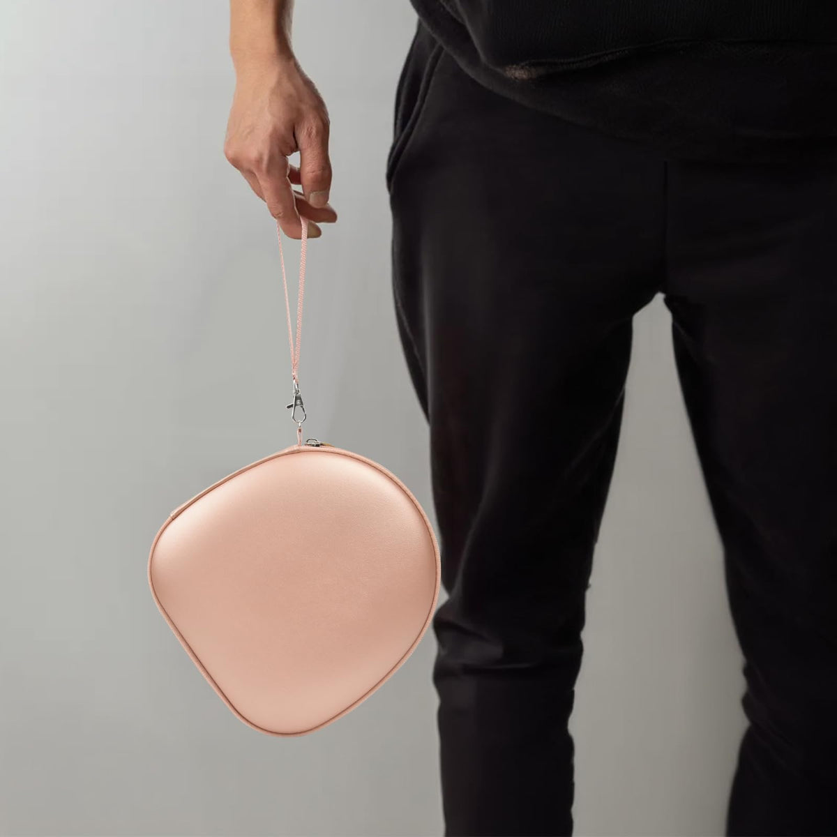 Person carrying the rose gold headphone case by its wrist strap
