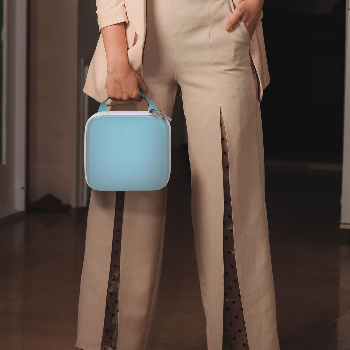Person carrying the light blue for NIIMBOT label maker case by its top handle