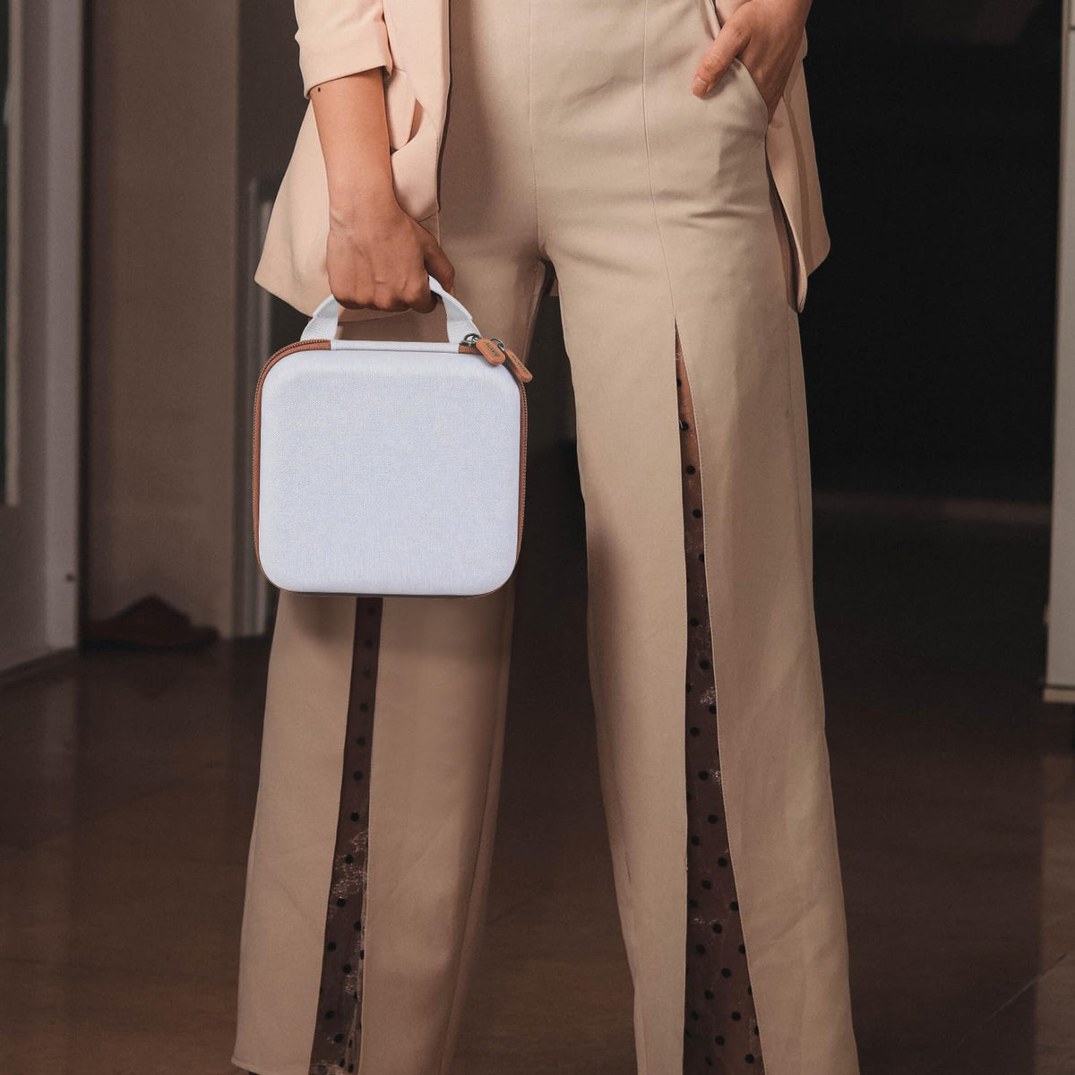 Person carrying the white and tan for NIIMBOT label maker case by its top handle