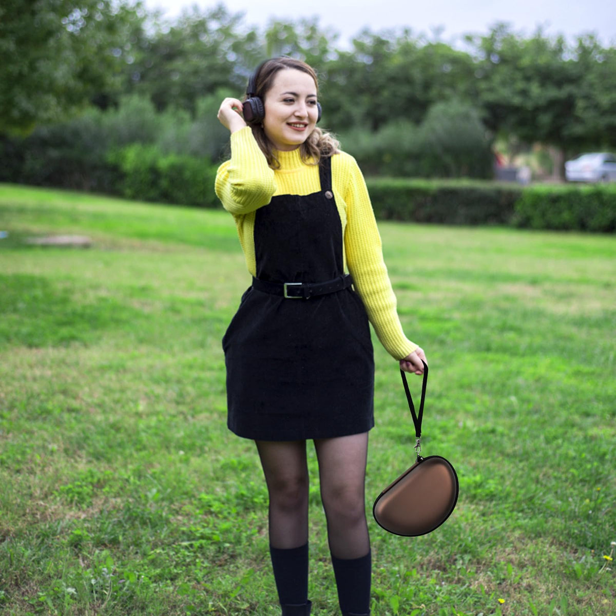 Woman carrying the brown headphone case by its wrist strap