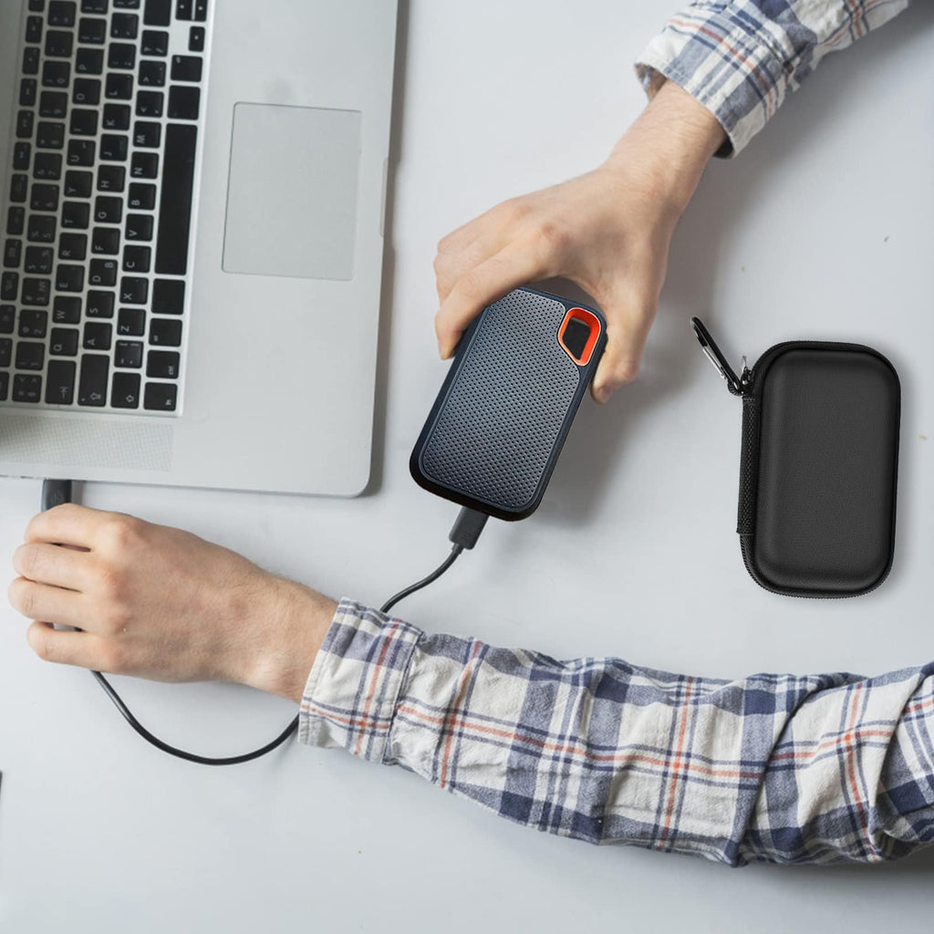 Black SSD organizer beside a for SanDisk drive connected to a laptop