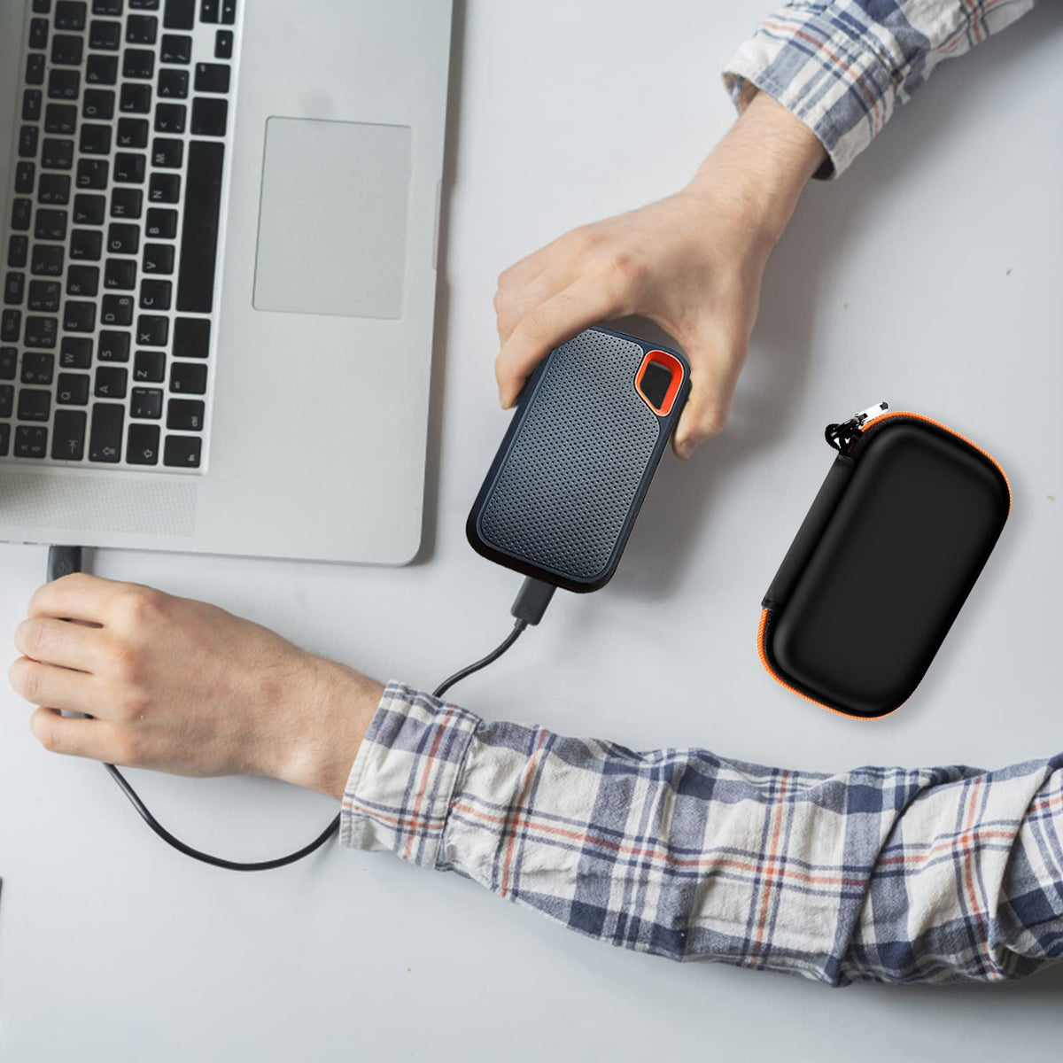 Black and orange SSD organizer beside a for SanDisk drive connected to a laptop