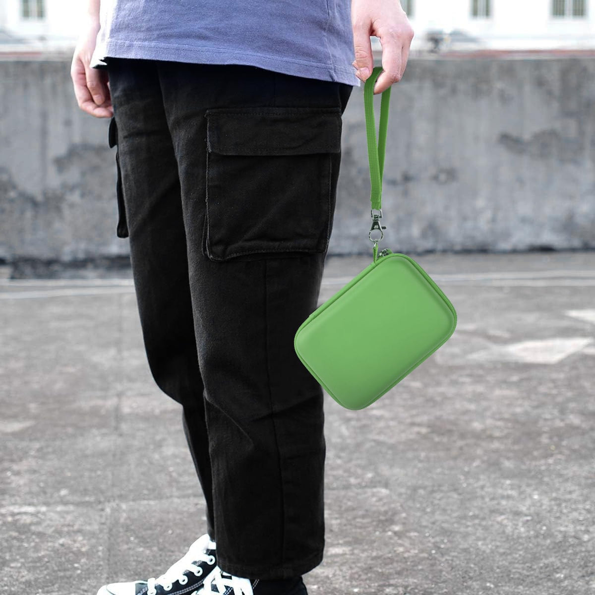 Green retro handheld console carrying case carried by the wrist strap outdoors