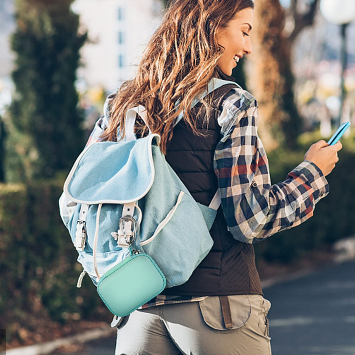 Mint green mini power bank case attached to a backpack for travel