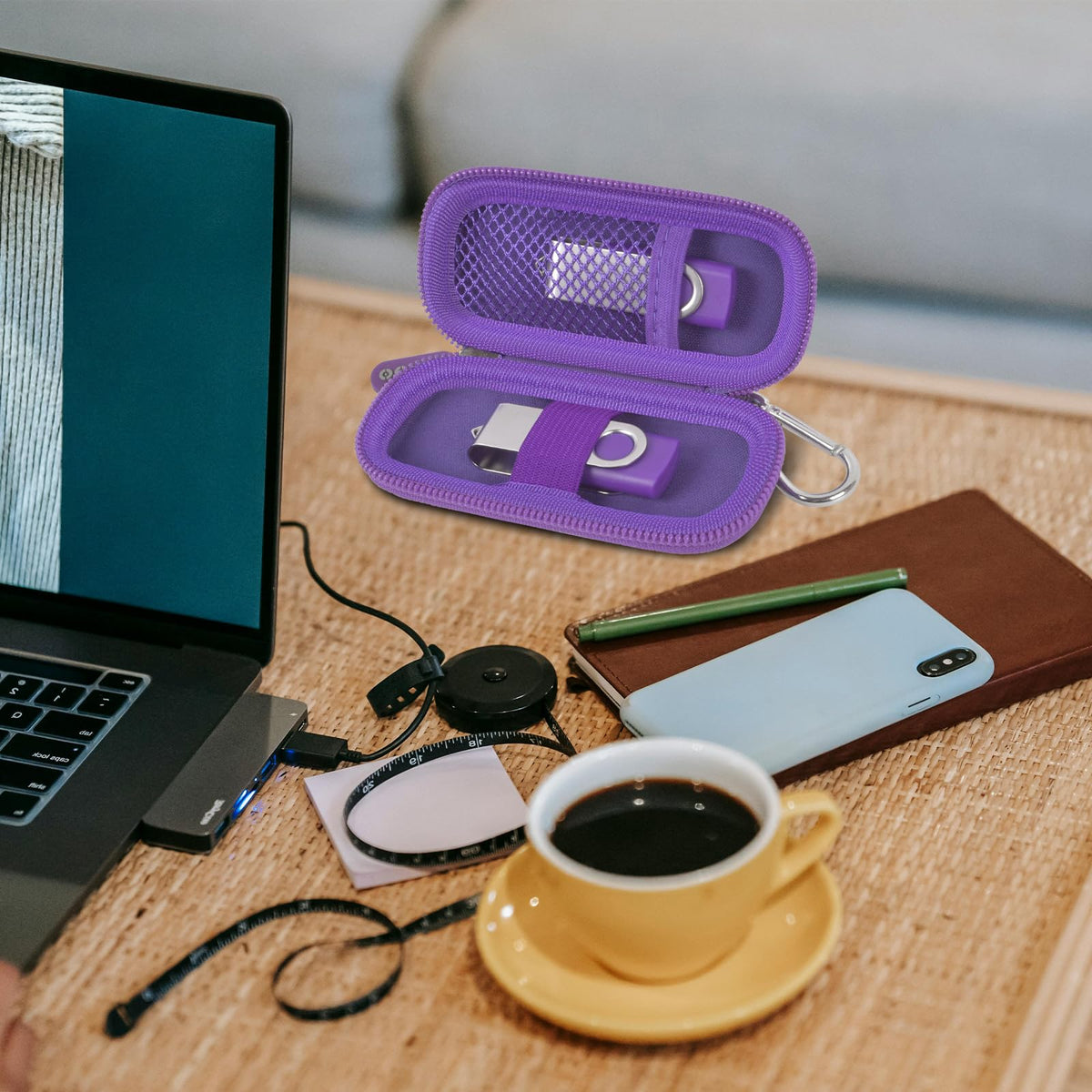 Purple USB flash drive and SD card storage case open on a desk with electronics accessories
